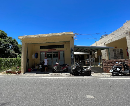 Two scooters are parked in front of a building on the side of the road.