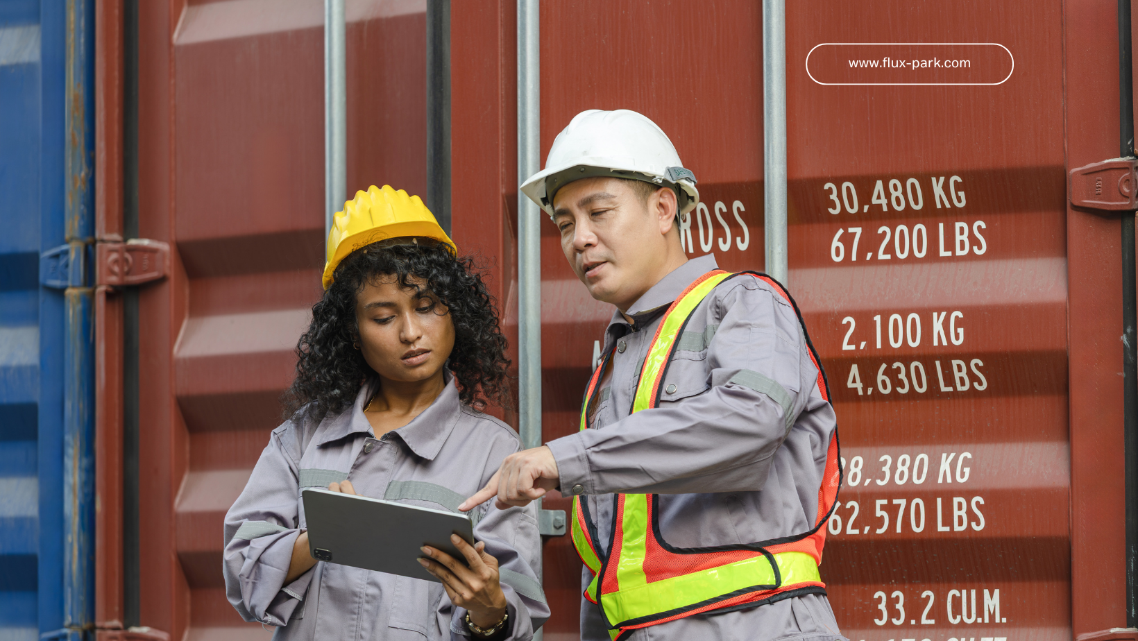 Two workers in safety gear review a tablet next to a shipping container, which has text indicating weight.