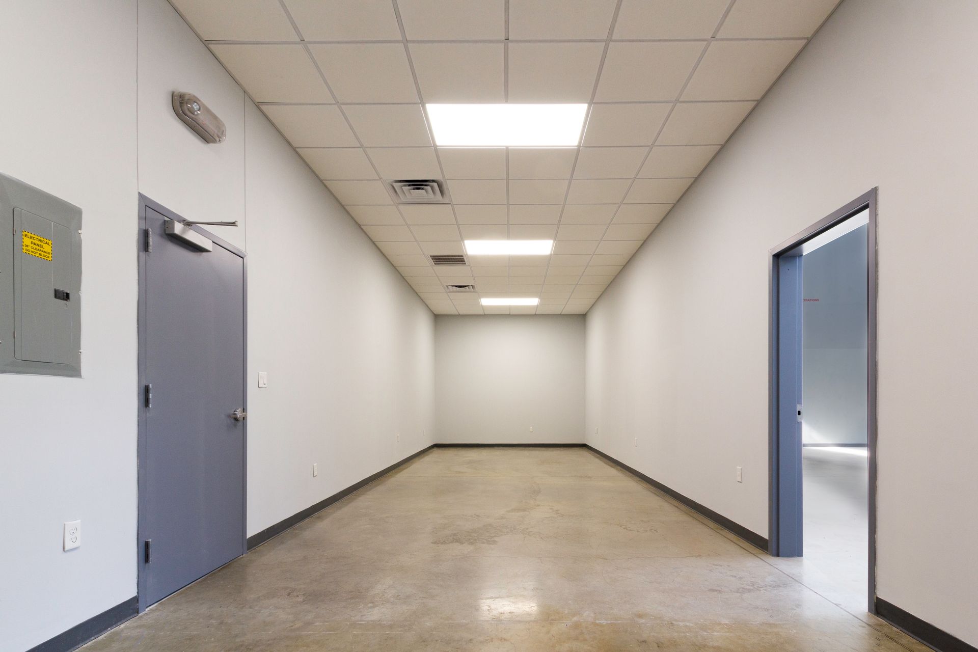 An empty hallway with two doors and a box on the wall.