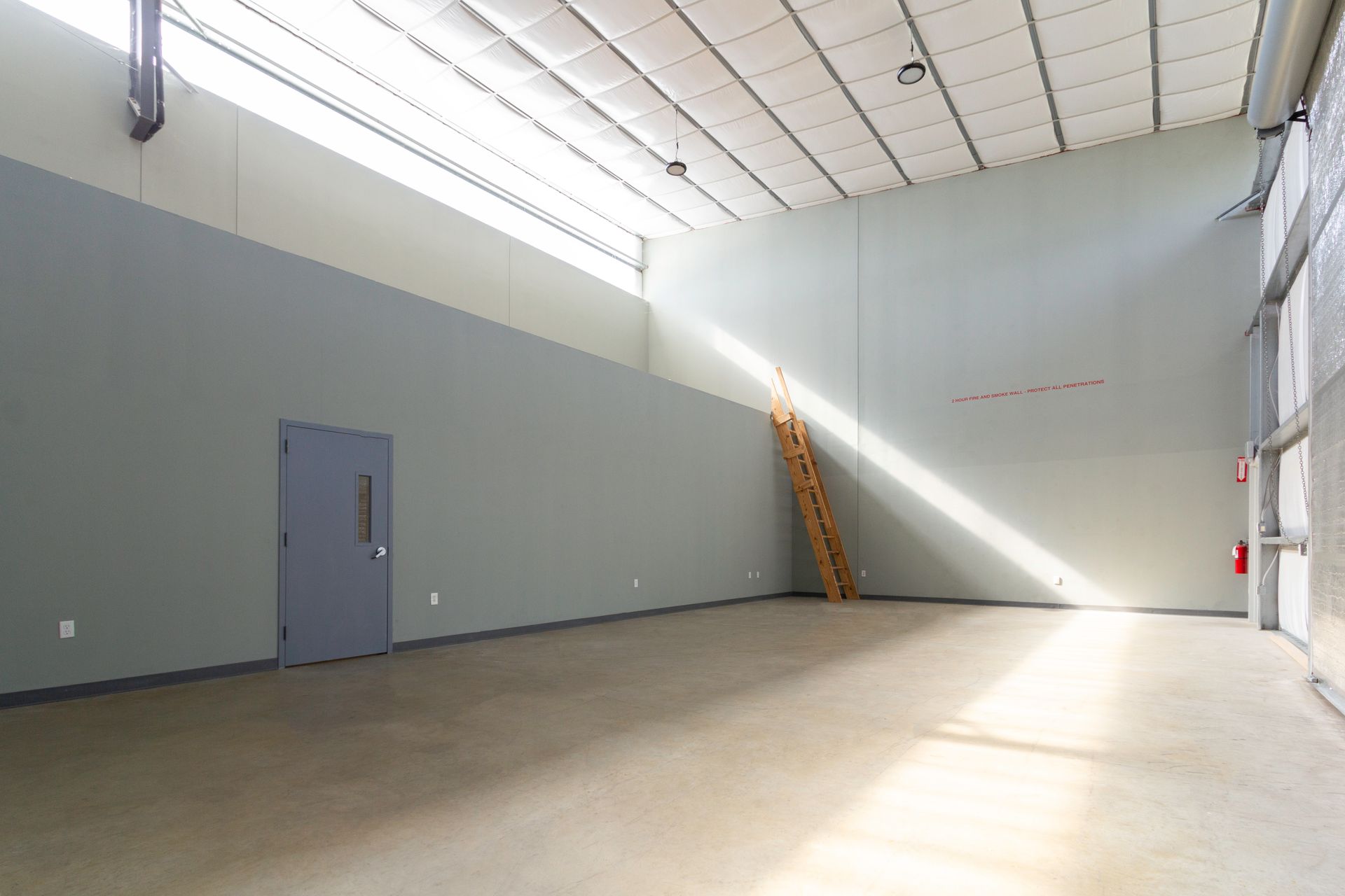 A large empty room with a ladder in the corner
