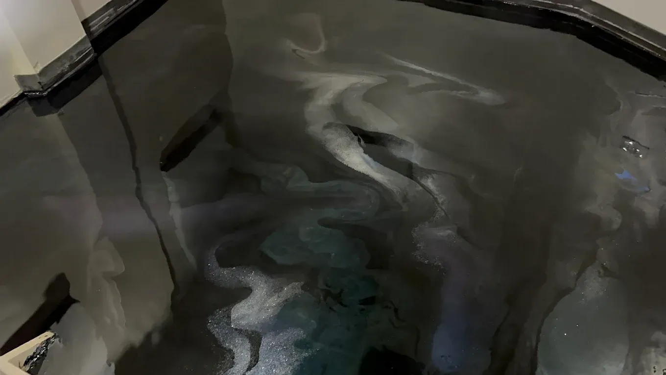 Abstract view of swirling gray and black liquid in a reflective container
