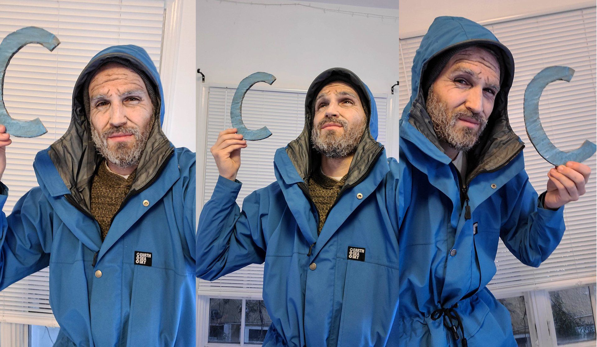 Man in blue jacket holds up the letter 