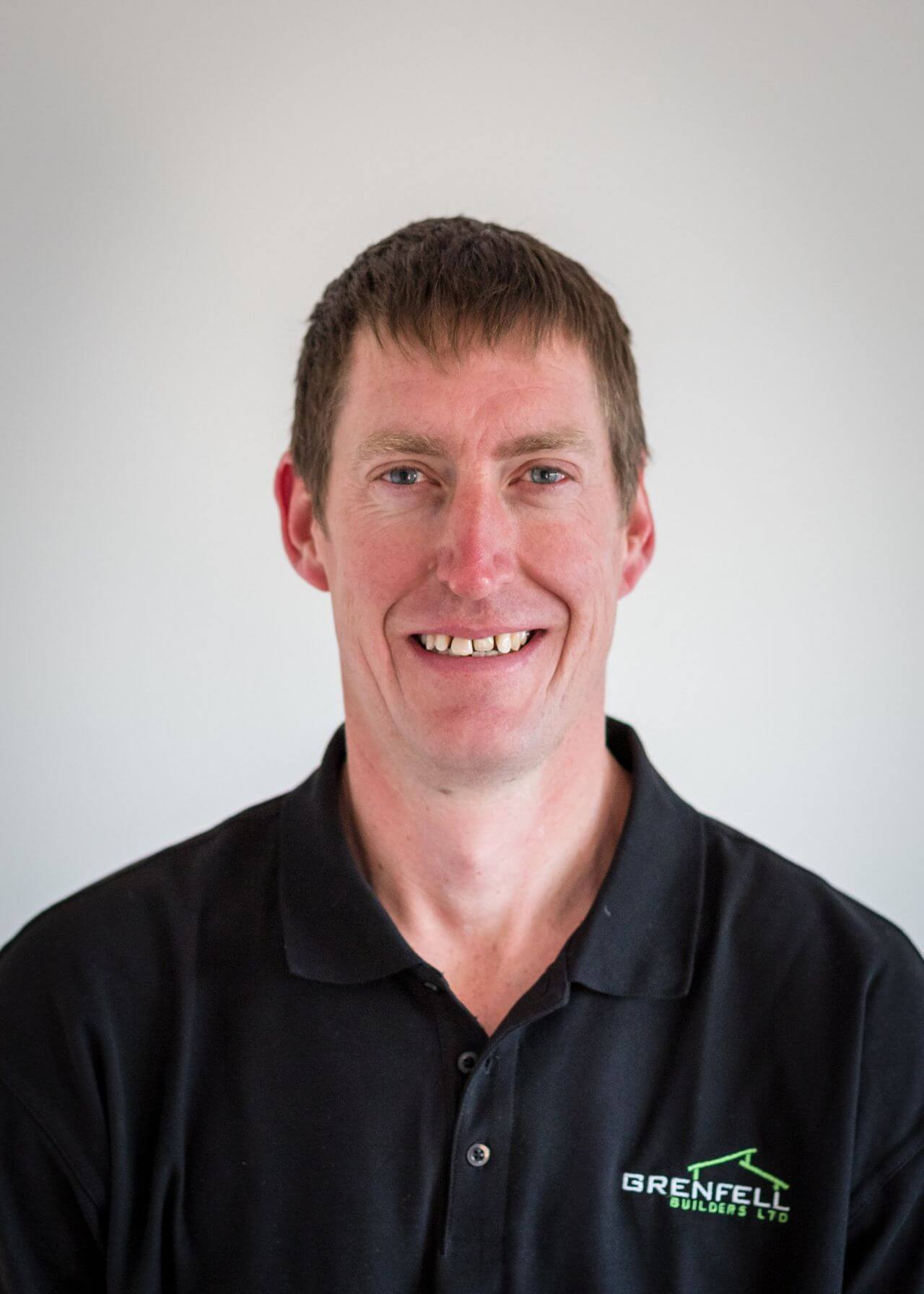a man wearing a black polo shirt is smiling for the camera .