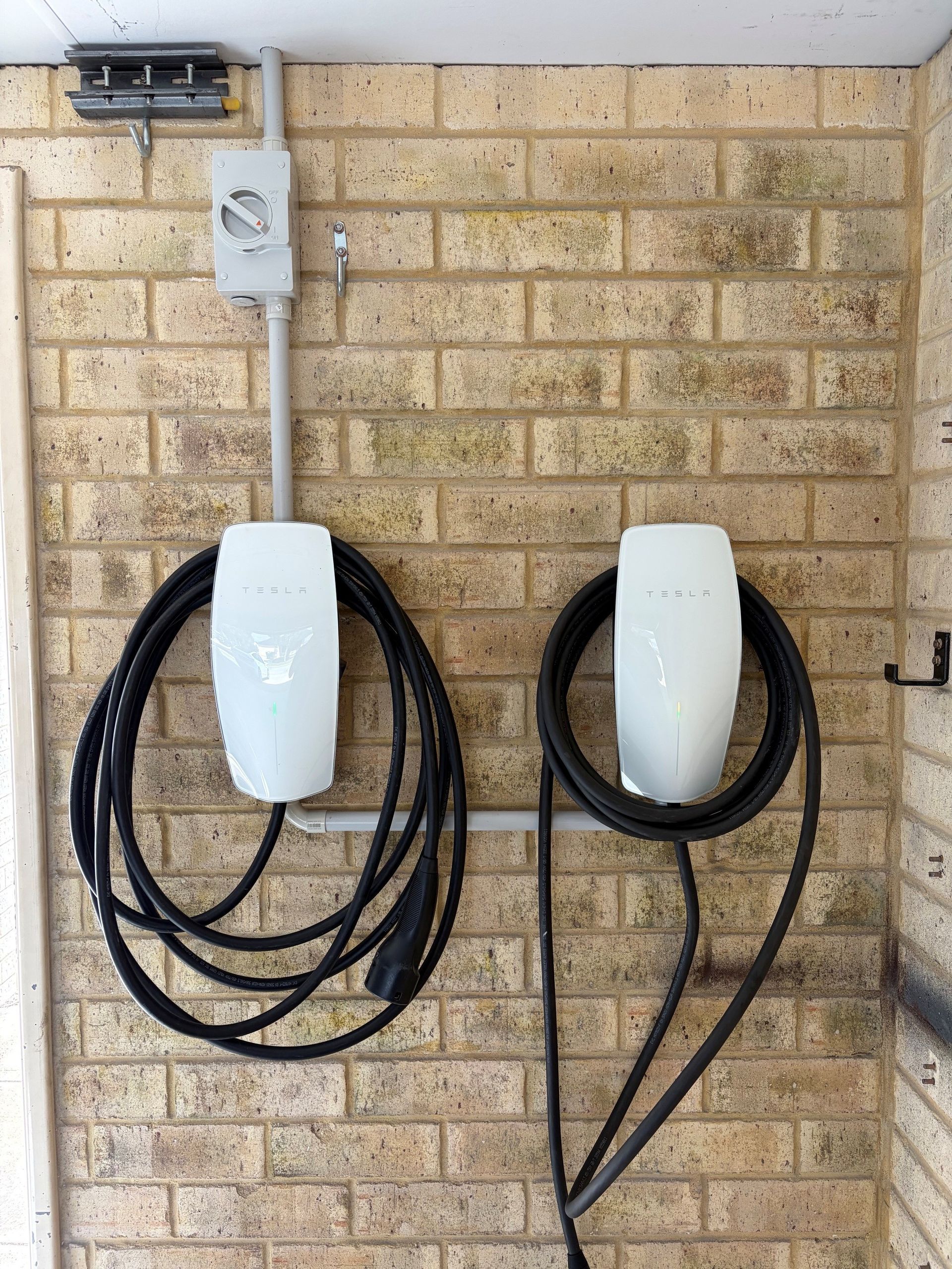 Person using a laptop at a wall-mounted charging station outdoors