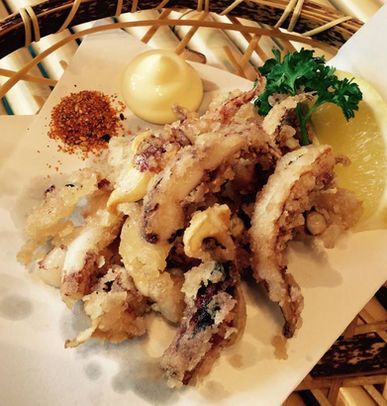 Fried squid tempura on a plate with mayonnaise, seasoning, and parsley garnish