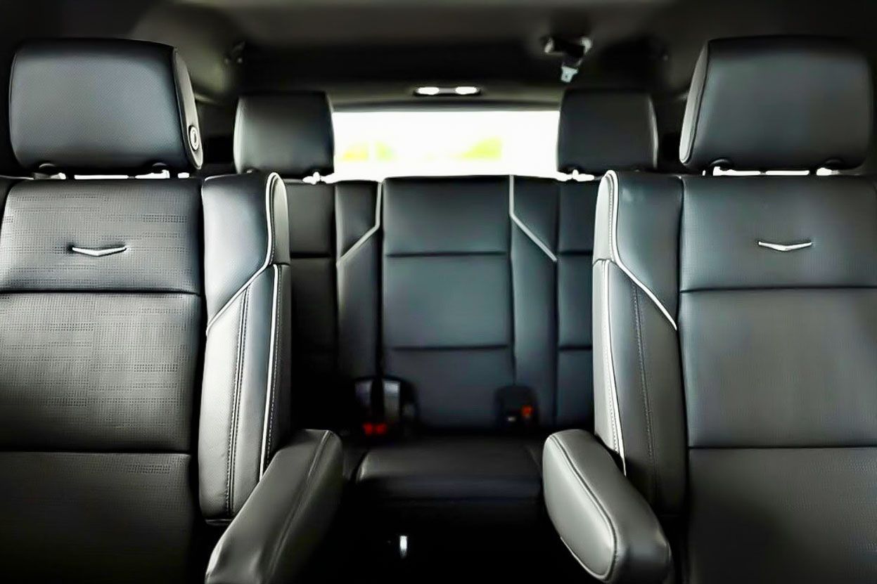 Interior view of a vehicle with black leather seats, including two captain's chairs and a rear bench seat.