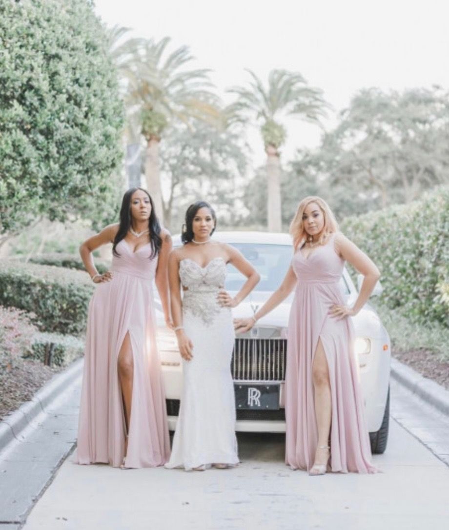 Three women in formal dresses pose by a white car, with a palm tree backdrop.Exotic Limo Orlando