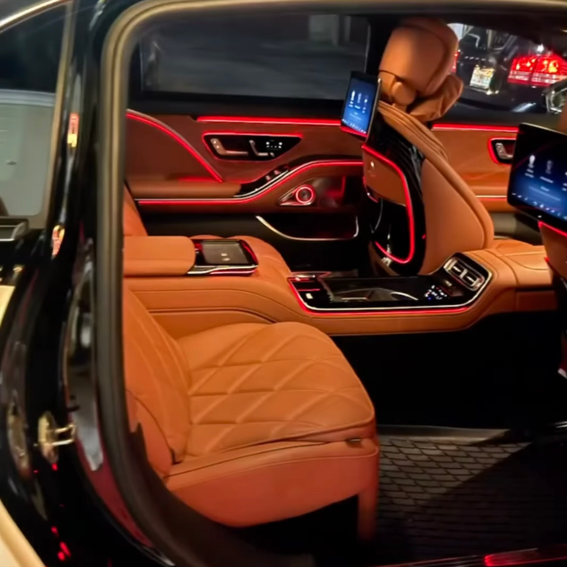 Exotic Limo Orlando Luxurious car interior with tan leather seats, ambient red lighting, and rear-seat entertainment screens.