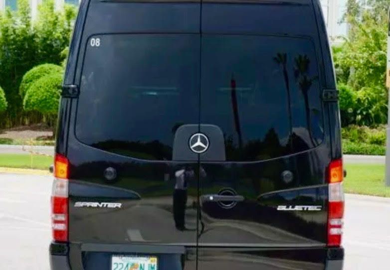 A black Mercedes-Benz Sprinter van viewed from the rear, showing tinted windows, the emblem, and a license plate.