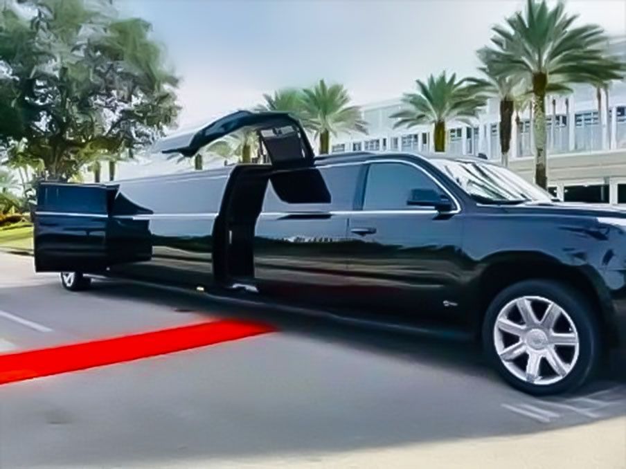 Black limousine with open doors on a red carpet, parked on a street with palm trees in the background.Exotic Limo Orlando