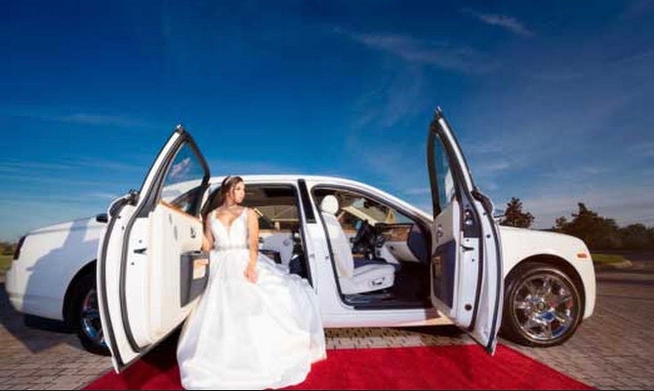 Exotic Limo Orlando Bride in white wedding dress exits a white luxury car with open doors on a red carpet,