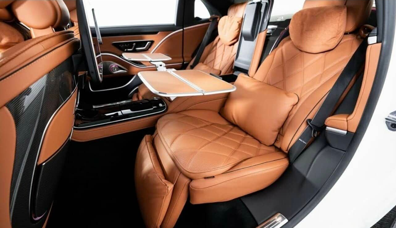 Exotic Limo Orlando Luxurious car interior with tan leather seats, fold-out tables, and a comfortable, reclined position.