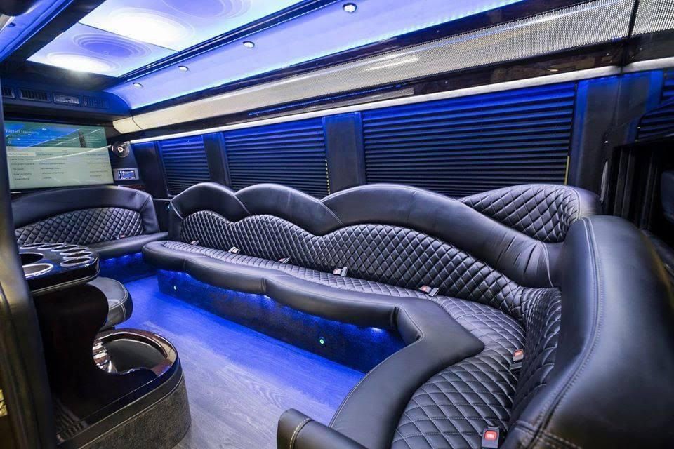 Interior of a black luxury van with diamond-stitched leather seating and blue LED lighting.