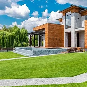 Lush garden with colorful shrubs, trees, and a white pergola in the background