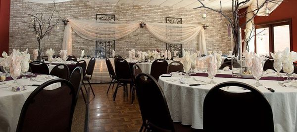 Elegant banquet hall with round tables, white tablecloths, black chairs, and a decorated backdrop. Elegant banquet hall with round tables, white tablecloths, black chairs, and a decorated backdrop.