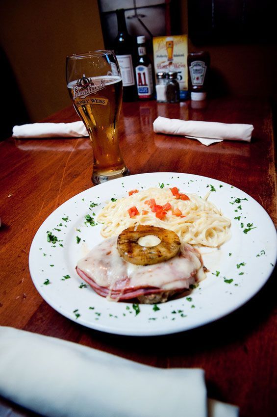 Plate of ham, poached egg, and potatoes on a restaurant table with a glass of beer