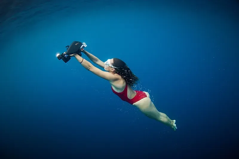 Femme avec son Sublue sous la mer en maillot de bain rouge