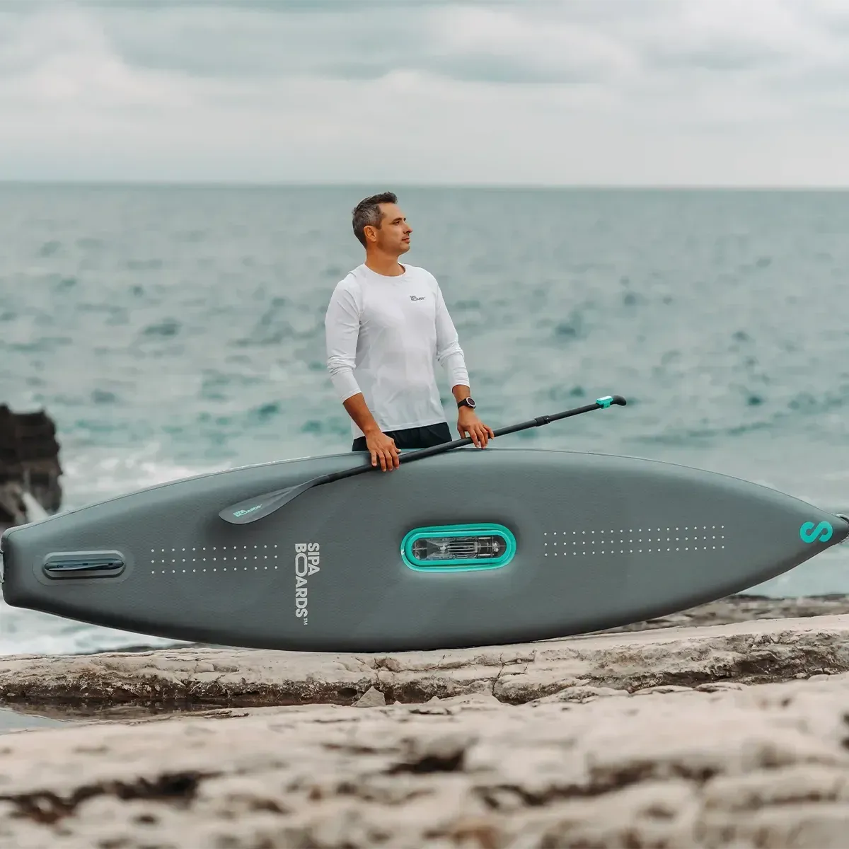 Homme qui. tient un sipaboard sur la plage