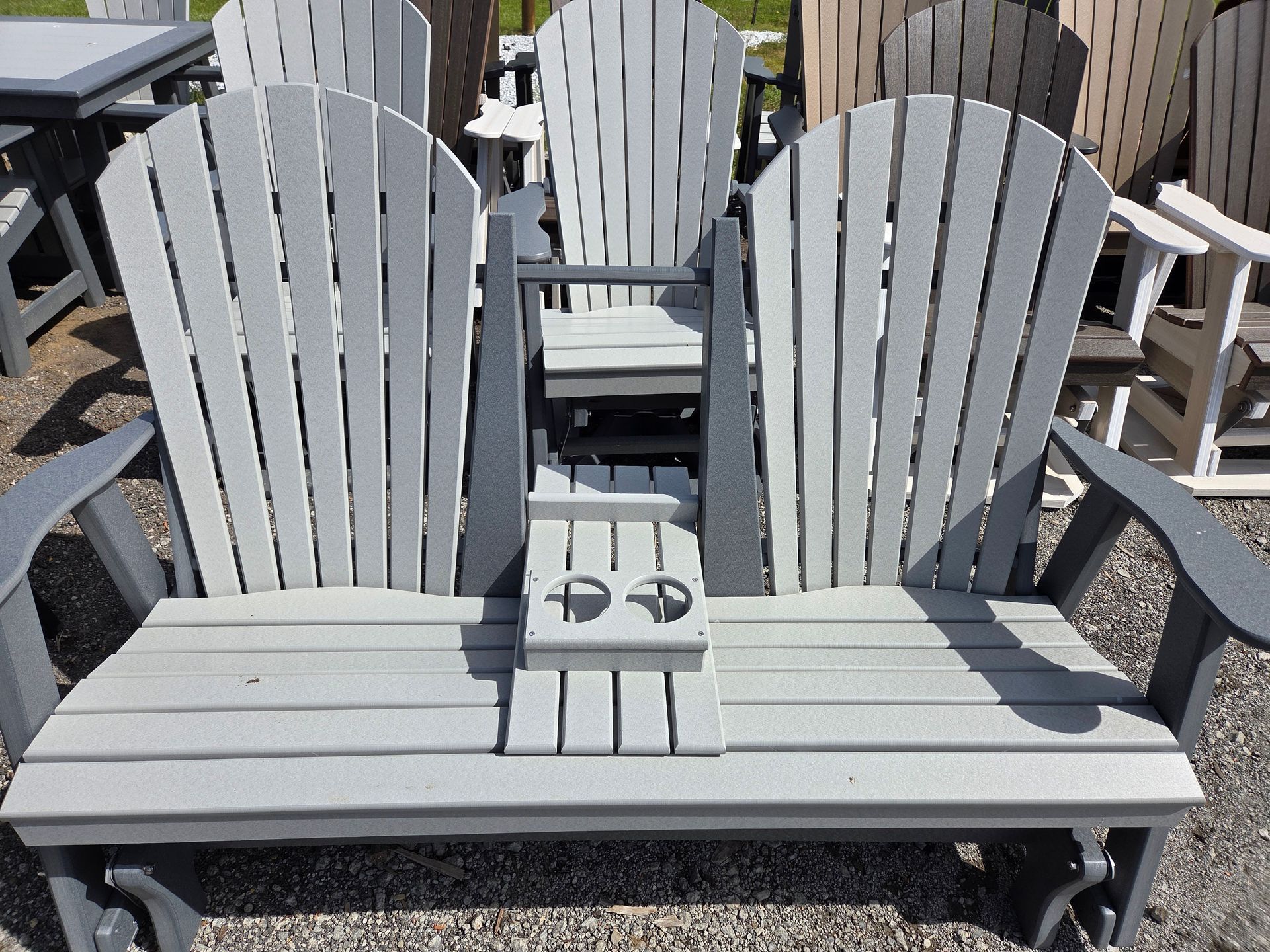 Gray wooden double Adirondack chair with a center cup holder on a patio