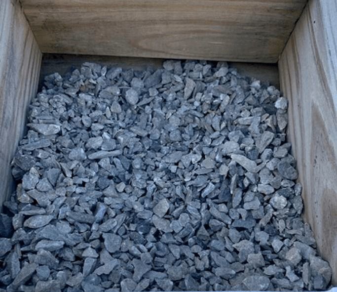 Wooden crate filled with small gray gravel stones