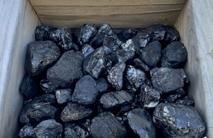 Open cardboard box filled with black, shiny coal chunks