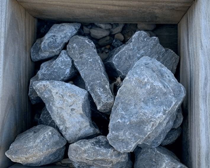Large gray rocks piled in a wooden crate.