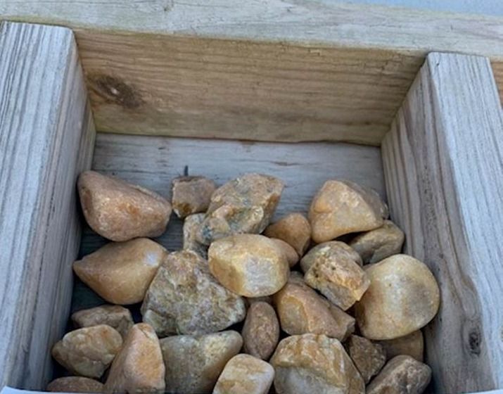 Small tan rocks piled in a wooden planter box
