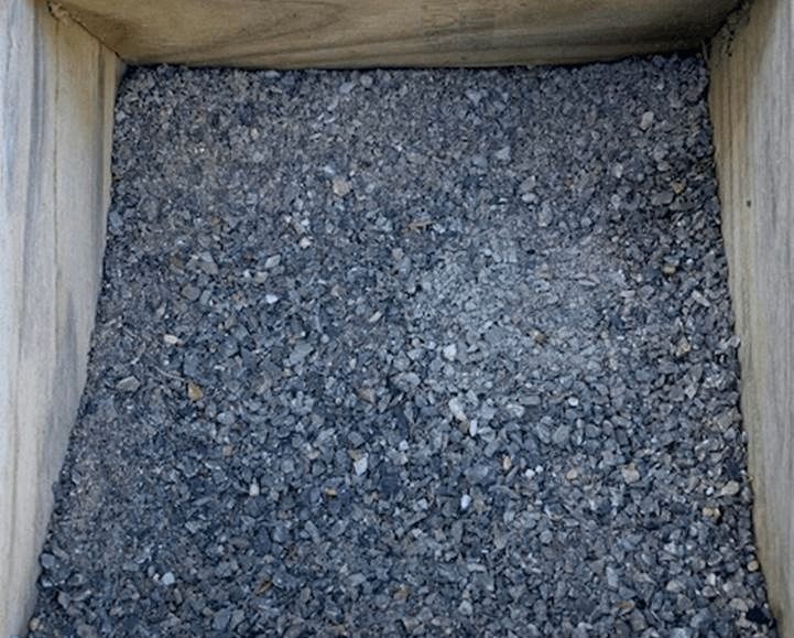 Wooden crate filled with gray gravel or crushed stone