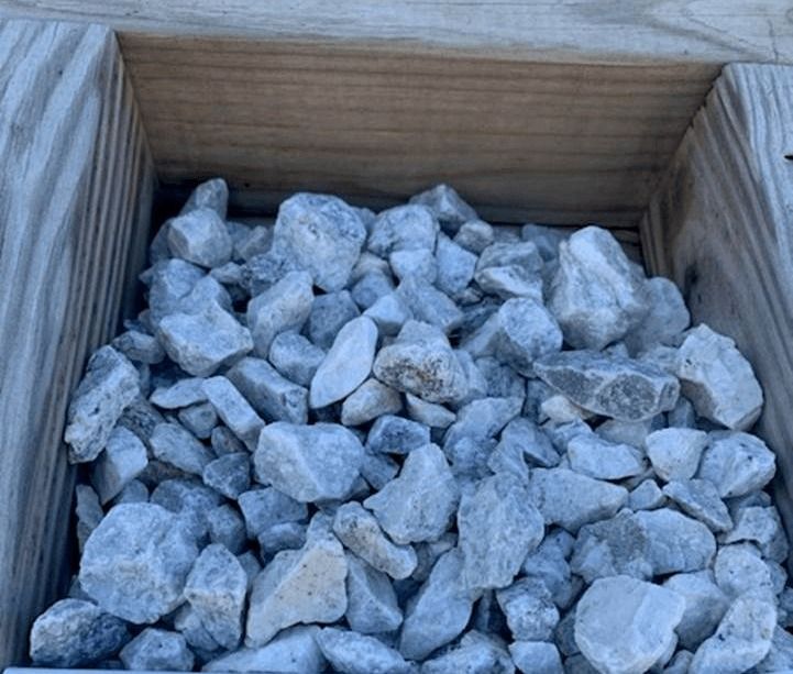 Wooden crate filled with small gray rocks or gravel