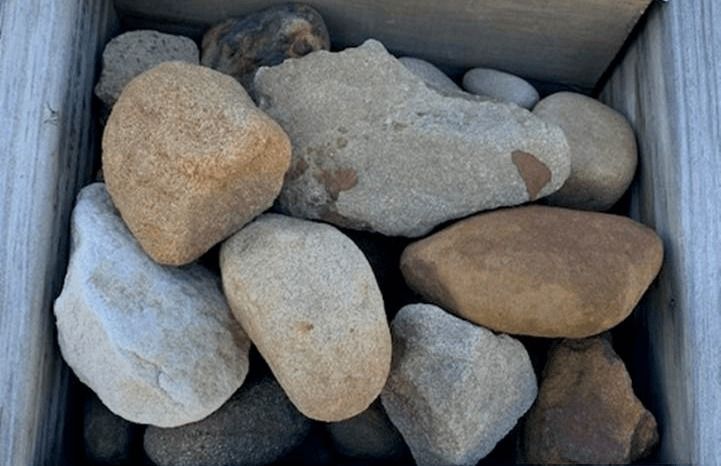 A box filled with smooth tan and gray stones