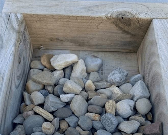Wooden crate filled with small gray and tan pebbles