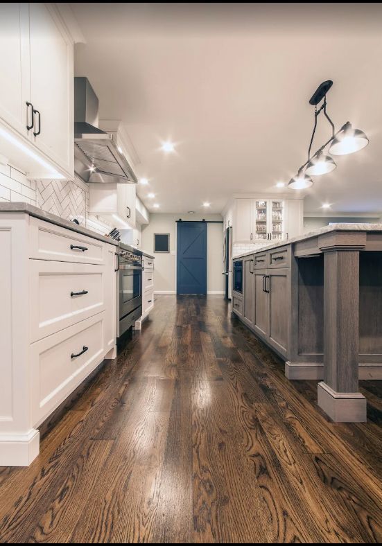 A kitchen with hardwood floors and white cabinets