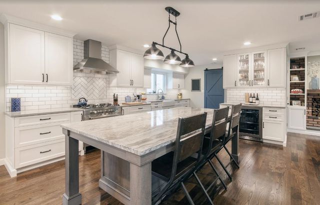 A kitchen with white cabinets , granite counter tops , and a large island.