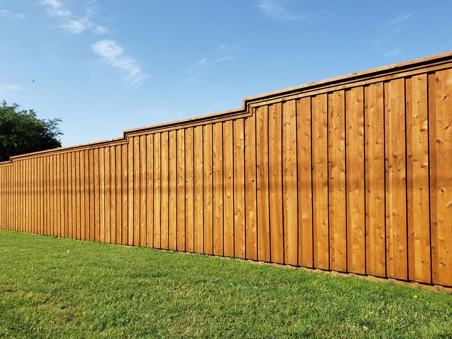 Wooden privacy fence beside a grassy lawn under a clear blue sky