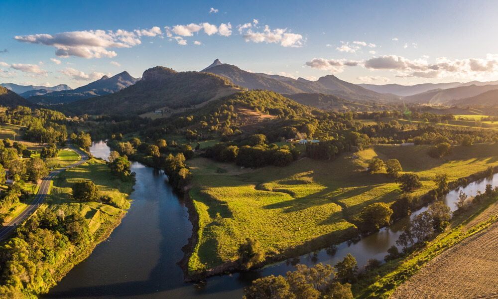 An Aerial View of a River Surrounded by Mountains and Trees  — Tweed Heads Coolangatta Taxi Service In Tweed Heads South, NSW