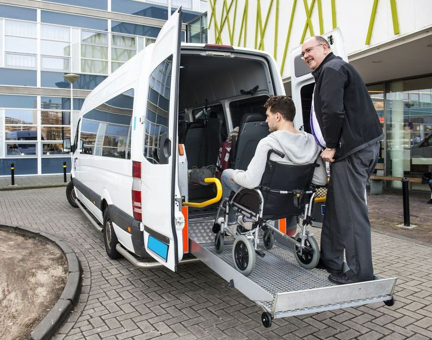 A Man Is Pushing A Man In A Wheelchair Into A Van — Tweed Heads Coolangatta Taxi Service In Tweed Heads, NSW