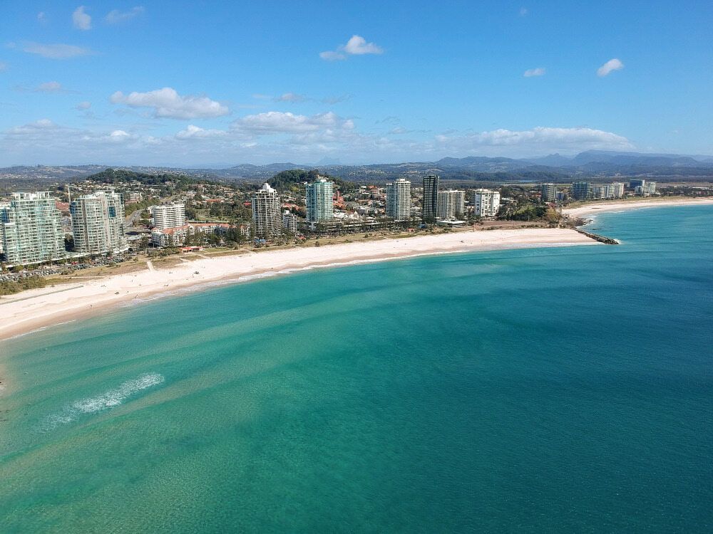 An Aerial View of a Beach With a City in the Background  — Tweed Heads Coolangatta Taxi Service In Kirra, QLD