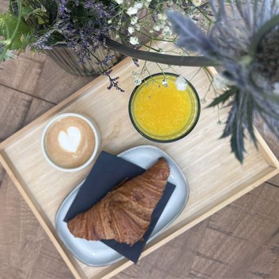 Breakfast option including a croissant, fresh orange juice and cappuccino.