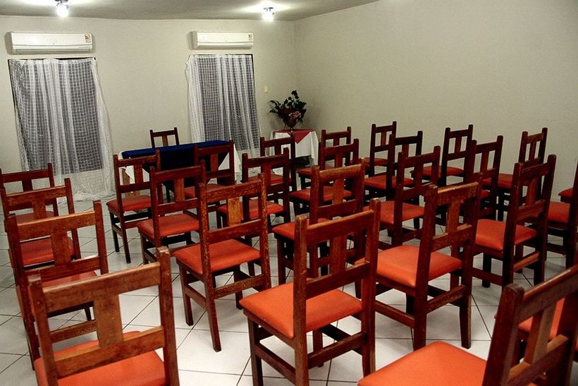 Fileiras de cadeiras de madeira em uma sala com assentos laranja