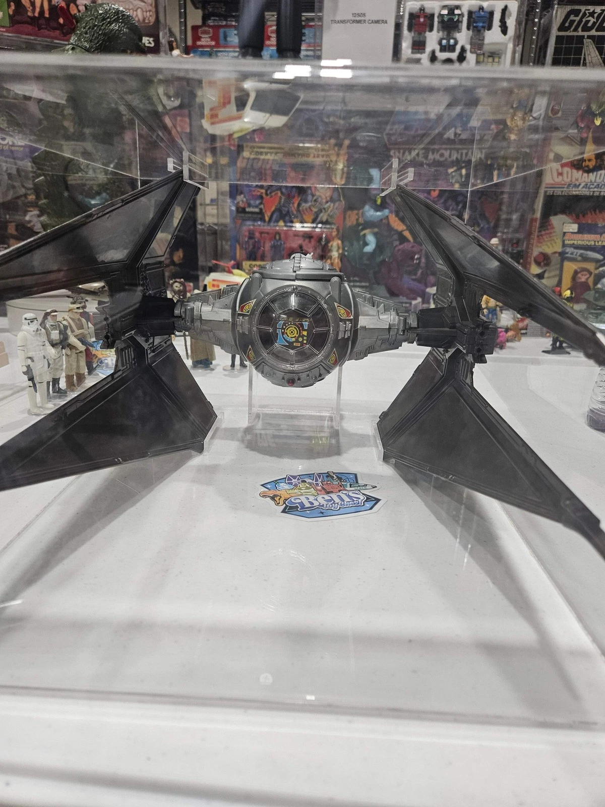 Star Wars TIE Silencer fighter on display in a glass case, with black wings and a central cockpit.