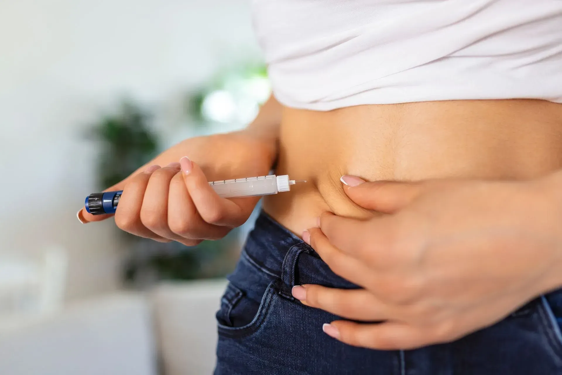 A woman is injecting herself with a syringe in her stomach.