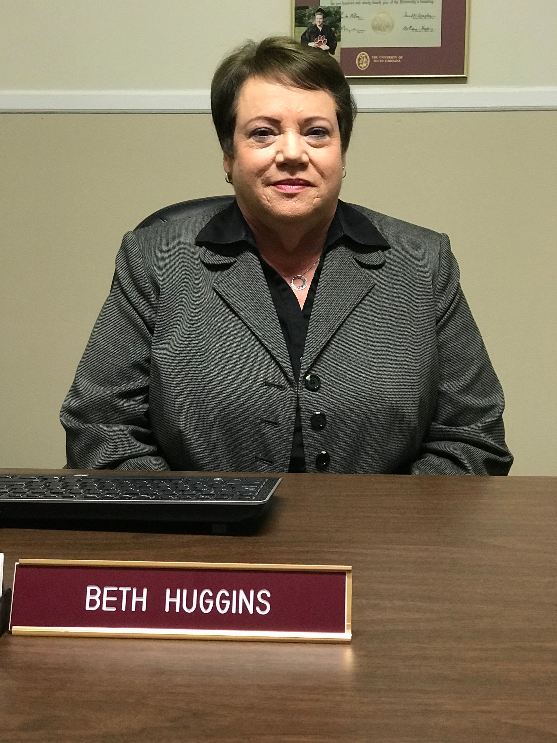 Beth huggins is sitting at a desk in front of a computer