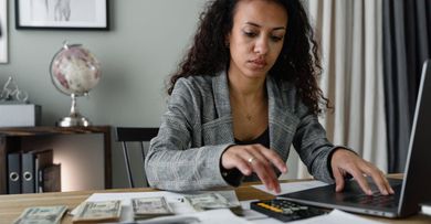 A woman is sitting at a table using a laptop computer.