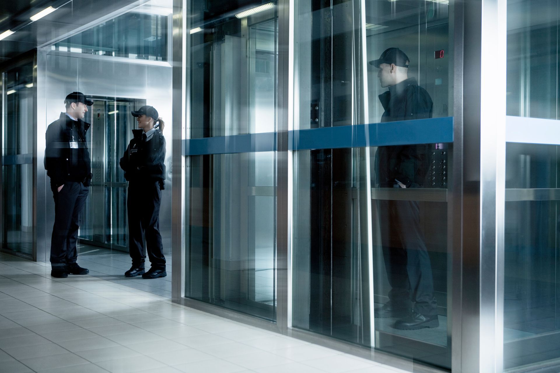 Security staff standing by glass doors in a modern office lobby.