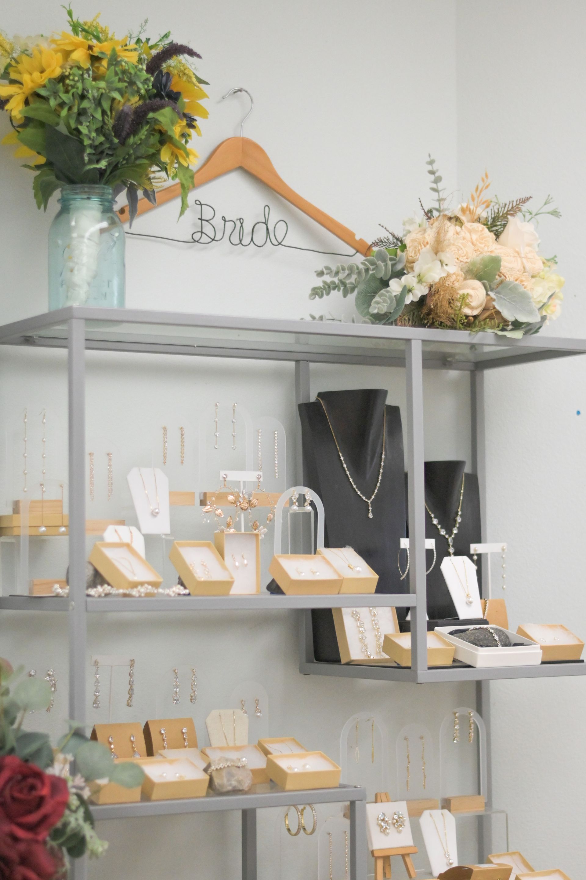 Jewelry display with necklaces, earrings, and floral arrangements. Includes a hanger that says 