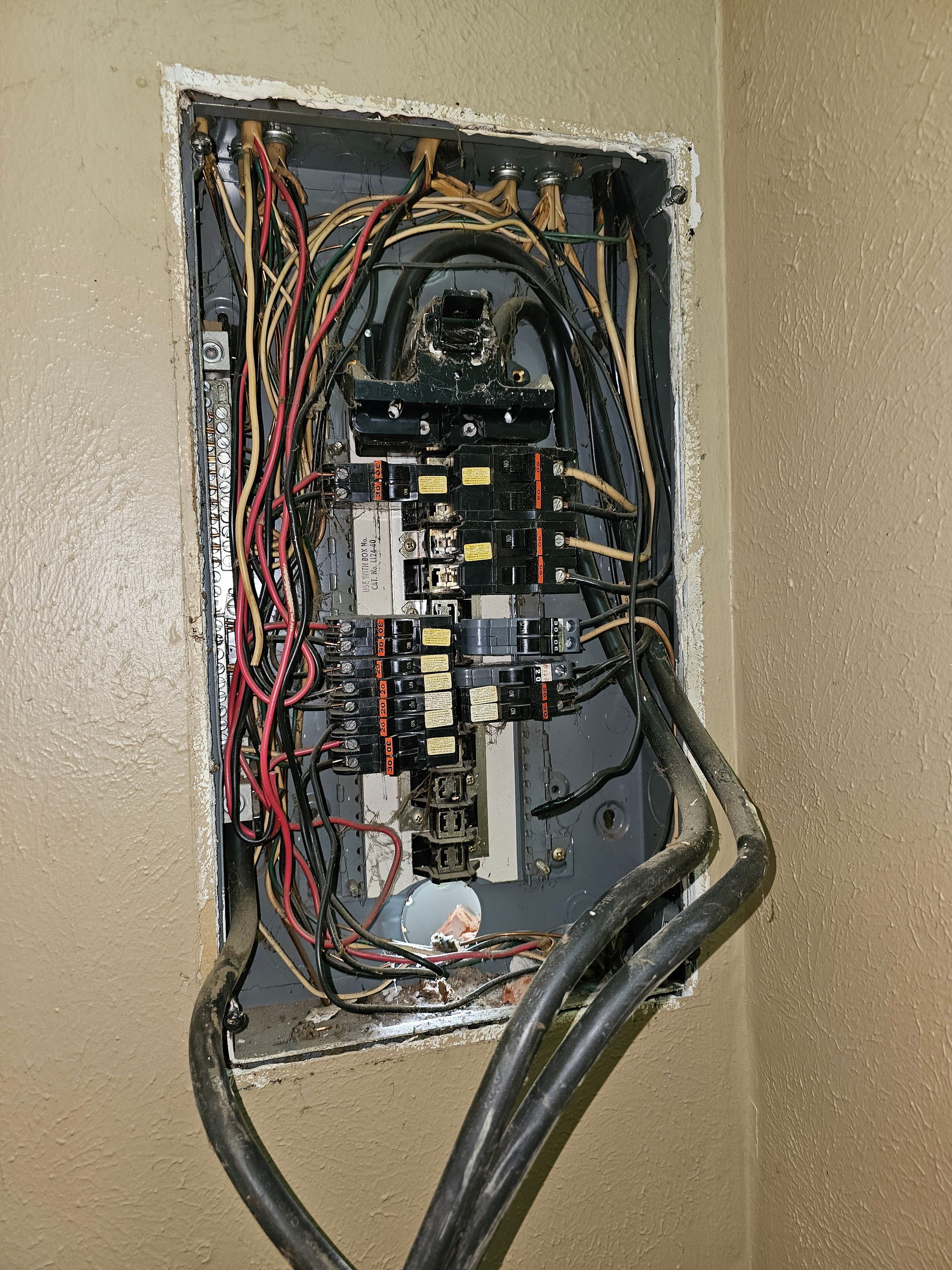 Open electrical breaker panel with wiring and circuit breakers exposed