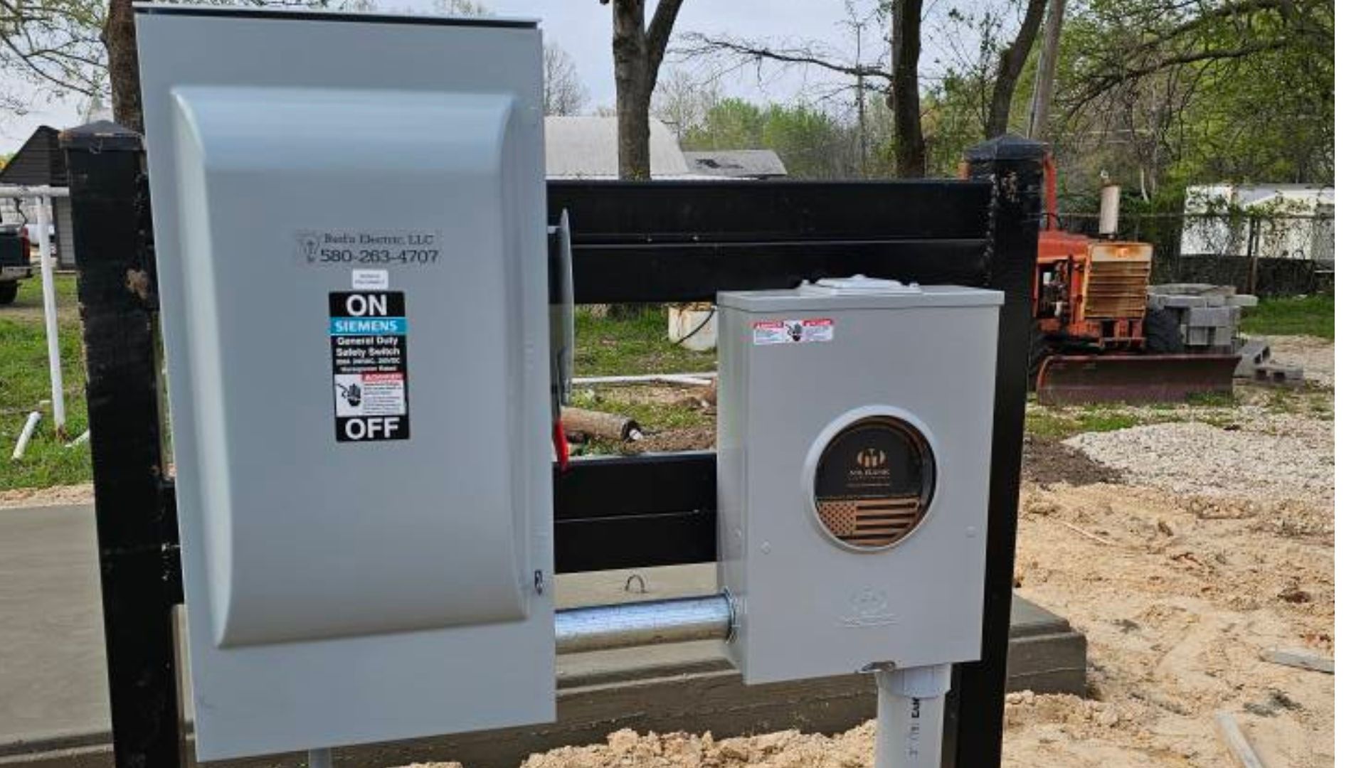 Gray electrical control panels mounted on a black frame outdoors at a construction site