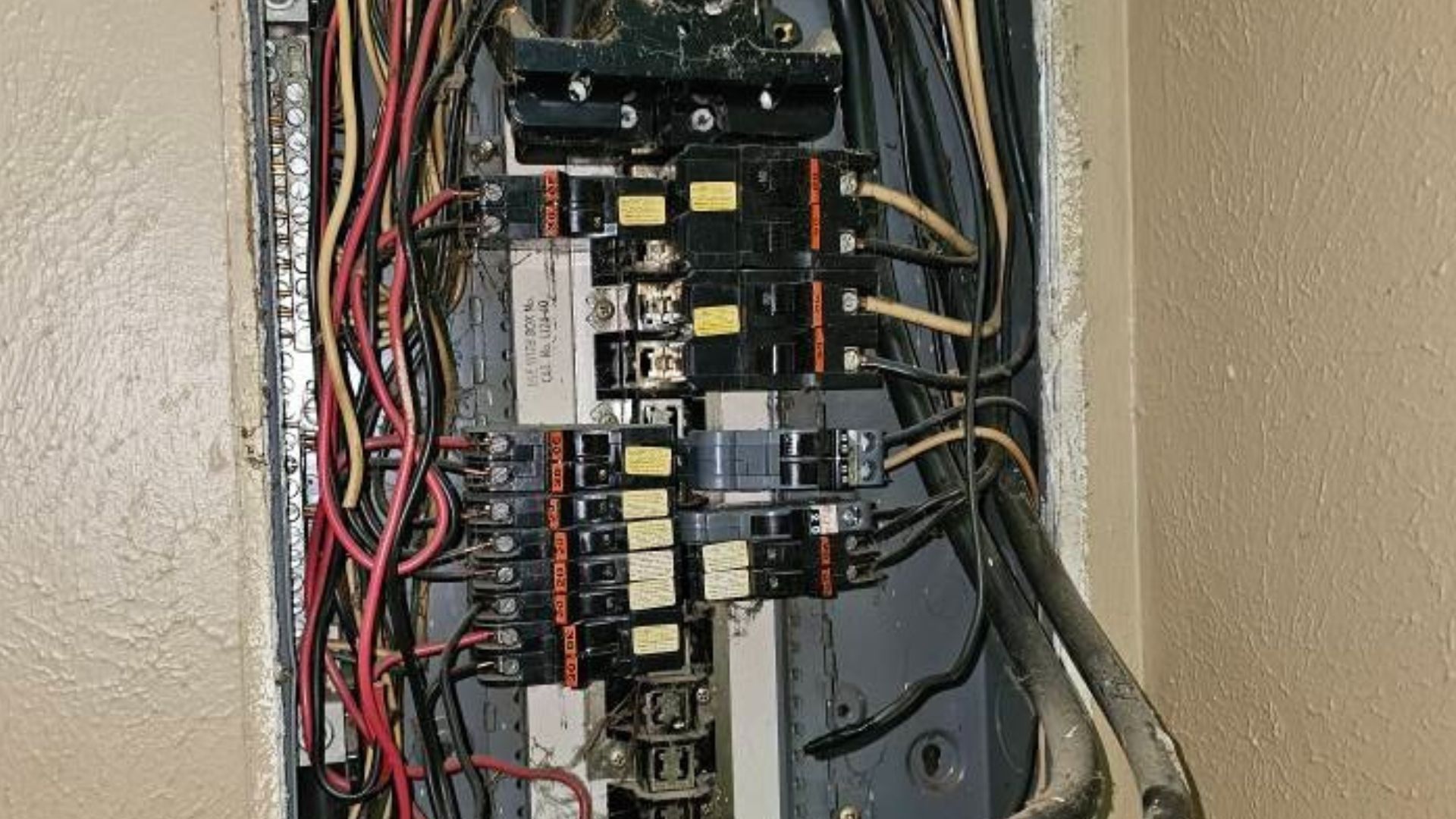 Open electrical breaker panel with wiring and circuit breakers exposed