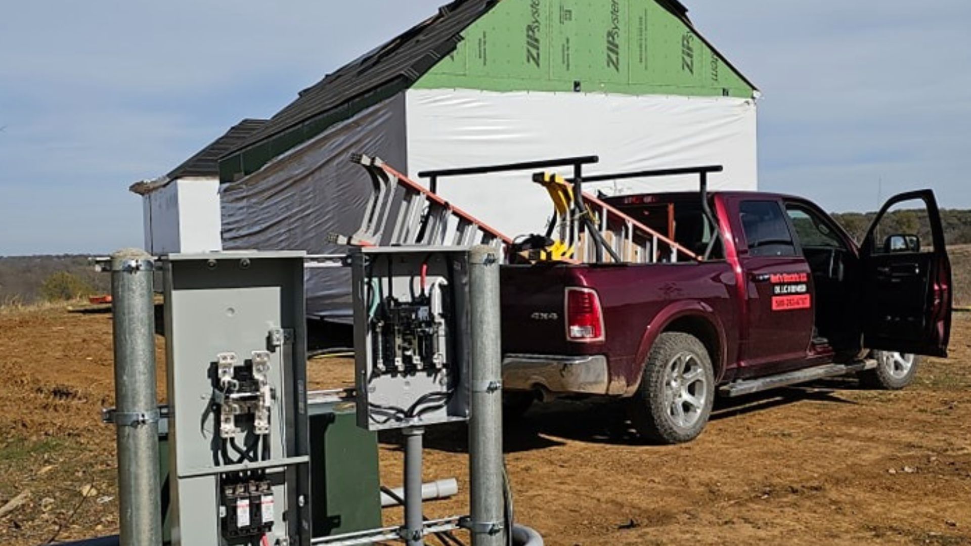 Red pickup truck beside a small shed, with hunting gear and open doors in a dry field