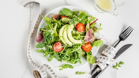 A picture of a salad and a measuring tape, signifying weight loss and healthy habits.
